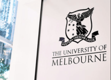 A picture of the University of Melbourne logo on a white wall.