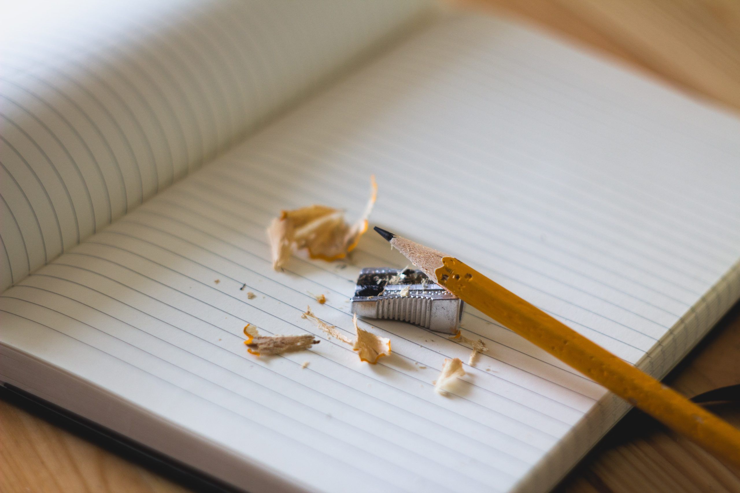 Image of a lined notebook with a pencil, pencil sharpener and pencil shavings