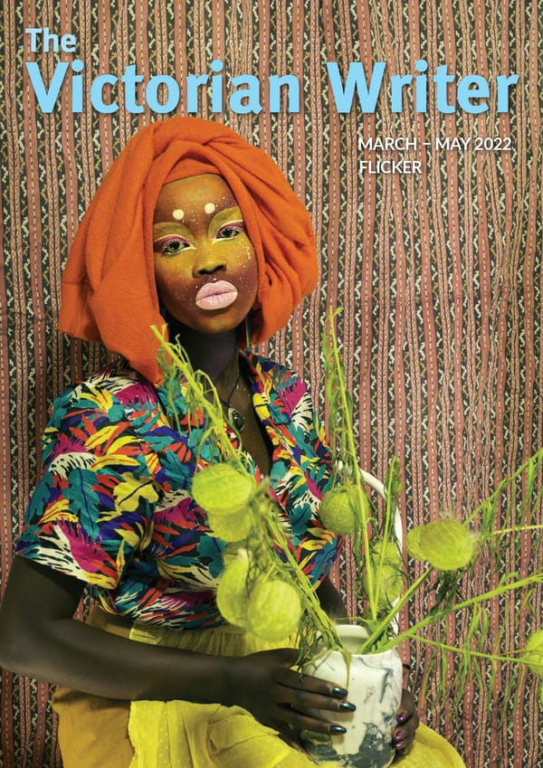 A cover image which is a self portrait of the artist, Atong Atem. She stands staring at the camera. She is wearing an orange scarf around her head, bright yellow and ping makeup, a bright colourful top and a yellow skirt. She is holding a green pot plant. The background is a textured wallpaper. The text reads "The Victorian Writer: March - May 2022. Flicker".