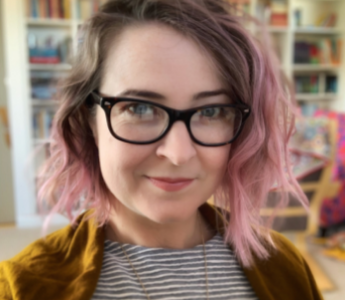 a portrait of Lili Wilkinson, a woman with pale peach skin and pink hair. She is smiling and wearing glasses