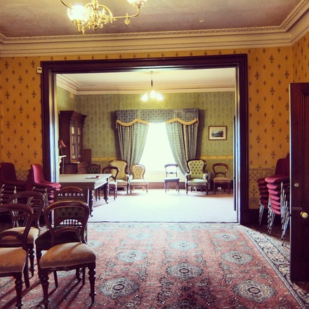 Photo of the Grand Room at Glenfern, featuring antique furniture, patterned carpets and sweeping curtains